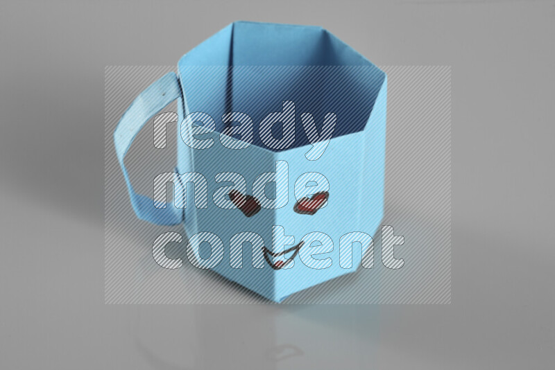 Origami cup on grey background