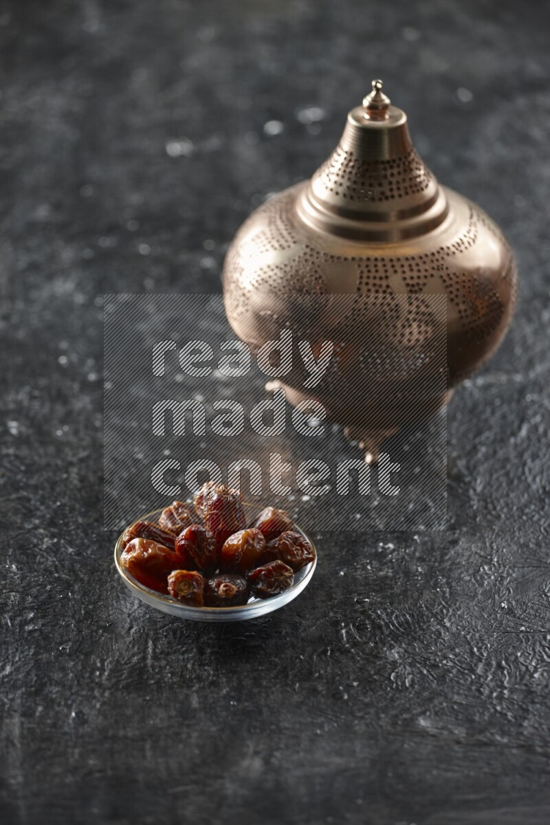 A golden lantern with different drinks, dates, nuts, prayer beads and quran on textured black background