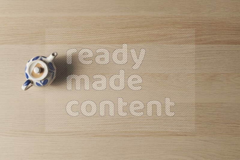 A pottery teapot on light wooden background