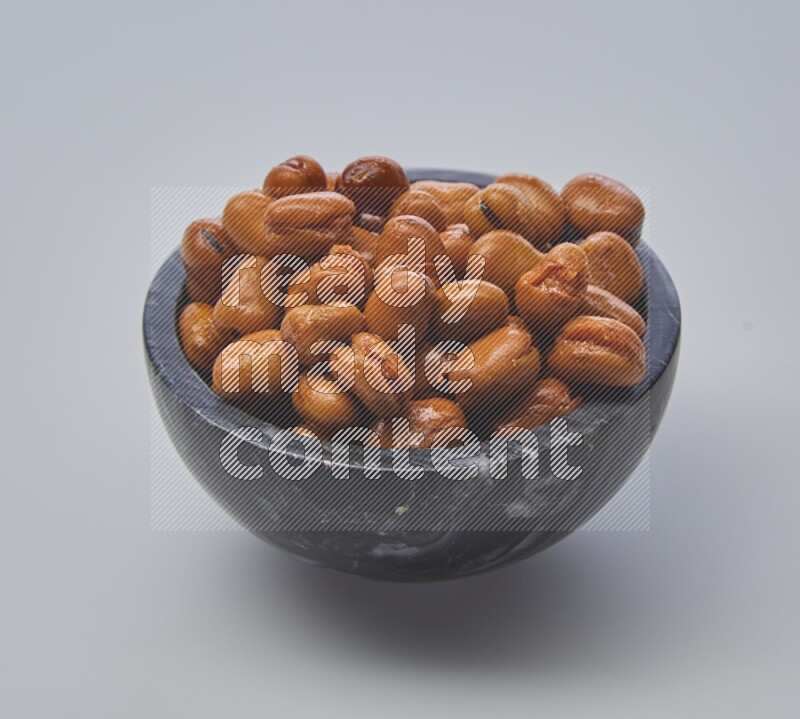 Close up shot of cooked fava beans (foul) in a container on white background