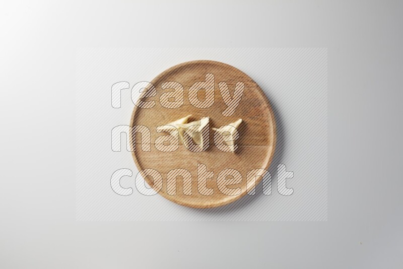 Three Sambosas on a wooden round plate on a white background