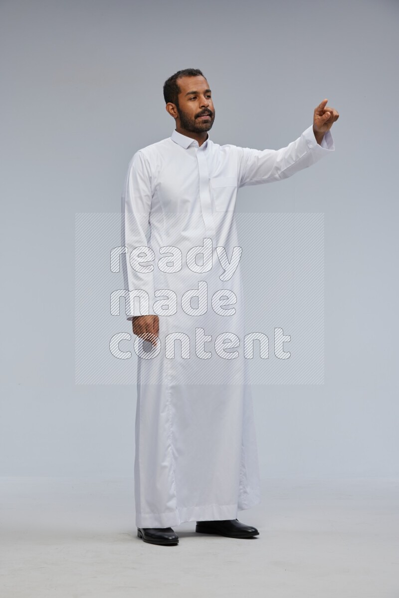 Saudi man Wearing Thob standing interacting with the camera on Gray background