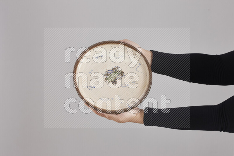 A woman in black abaya holding different pottery essentials in different positions