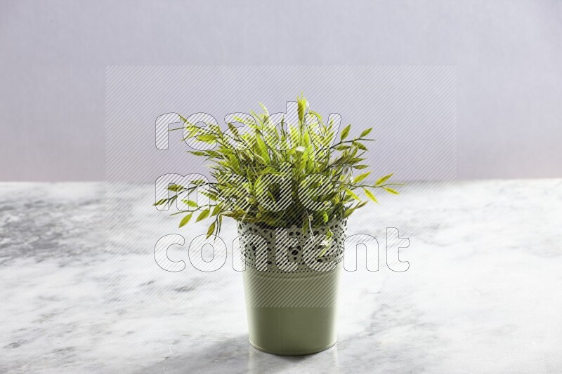 Artificial plant in green decorative pot on grey marble background