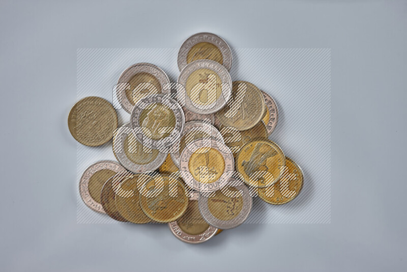 A close-up of scattered mixed Egyptian coins such as One pound, 50 and 25 piasters on grey background