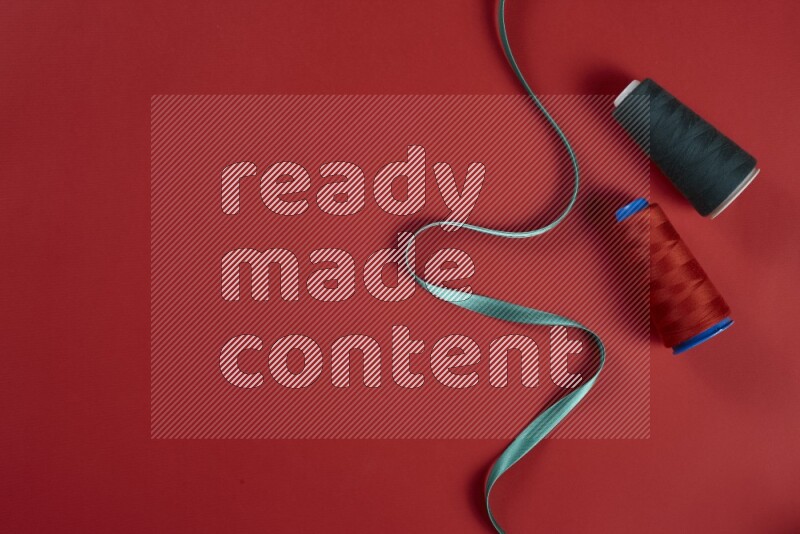 مجموعة من أدوات الخياطة والتفصيل خضراء وحمراء اللون على خلفية حمراء