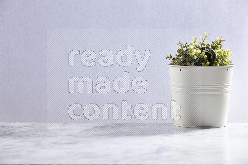 Green artificial plant in white pot on grey marble background