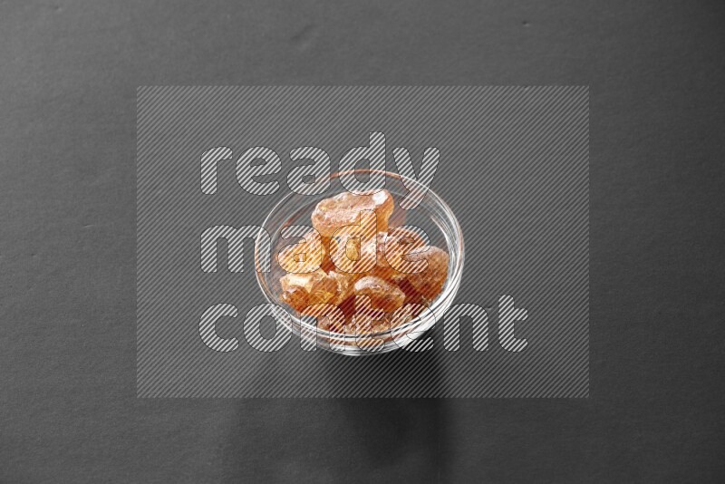 A glass bowl full of gum arabic on black flooring