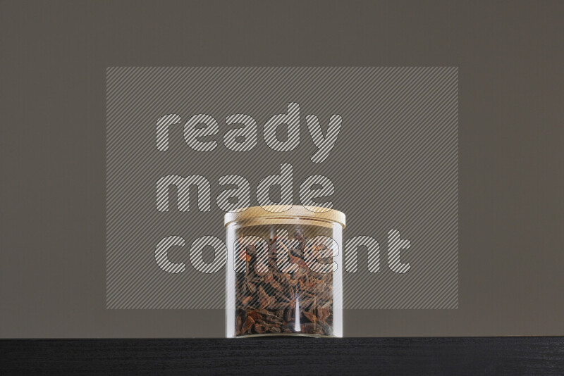 Star anise in a glass jar on black background