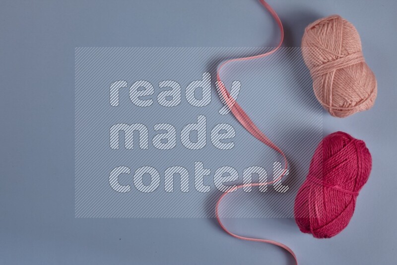 A pink collection of sewing and tailoring tools arranged on a blue background