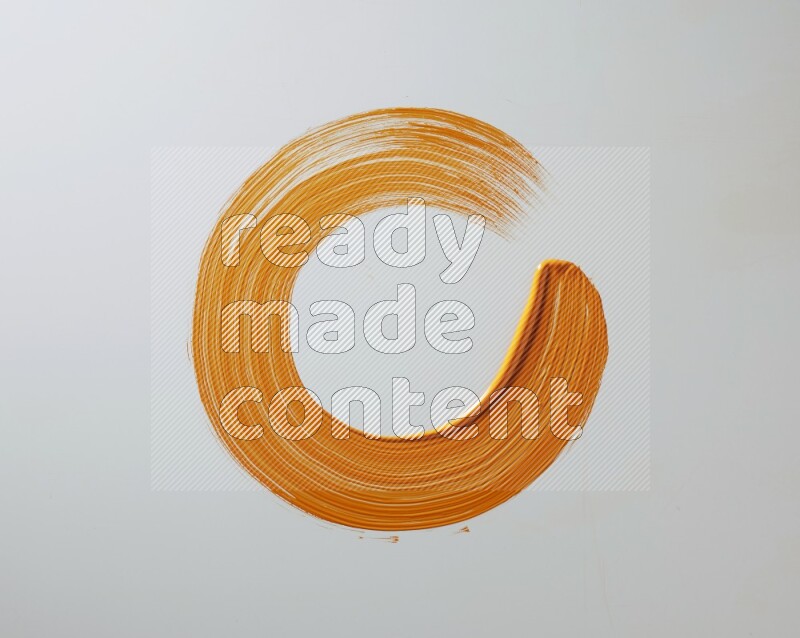 An orange circular painting brush stroke on white background