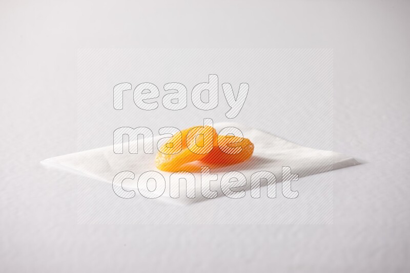 Two dried apricots on a piece of paper on a white background in different angles
