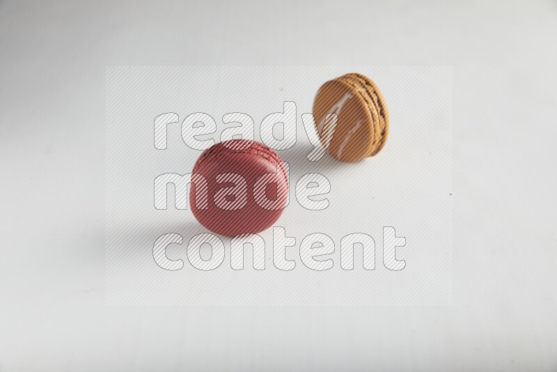 45º Shot of of two assorted Brown Irish Cream, and Red Velvet macarons on white background