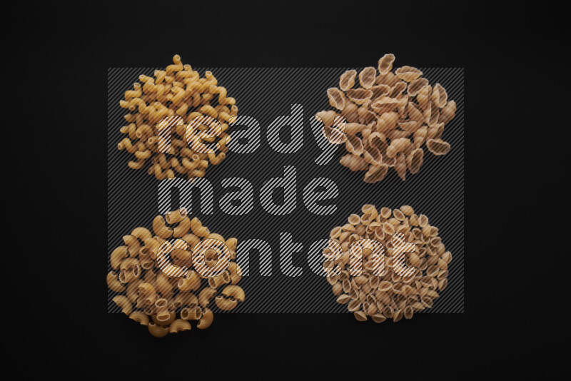Different pasta types in bunches on black background