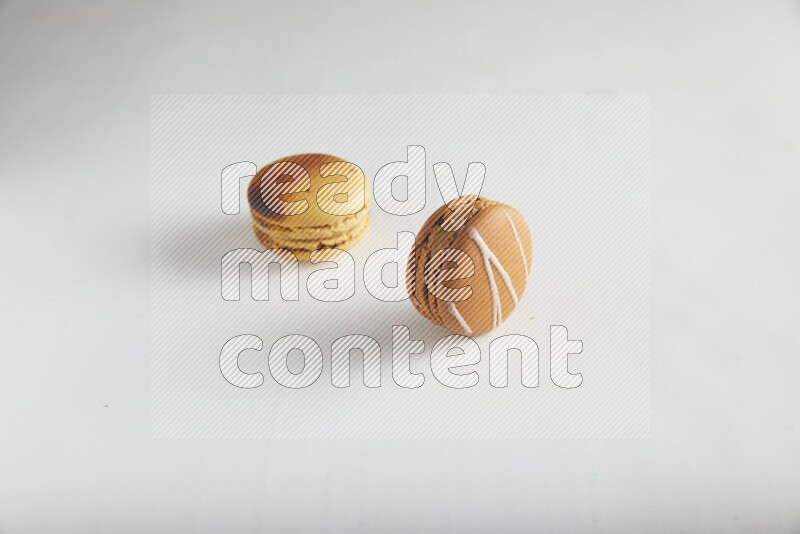 45º Shot of of two assorted Brown Irish Cream, and Yellow Crème Brulée macarons on white background