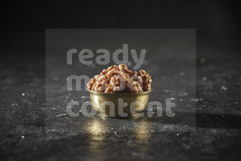 Nuts in a metal bowl in a dark setup