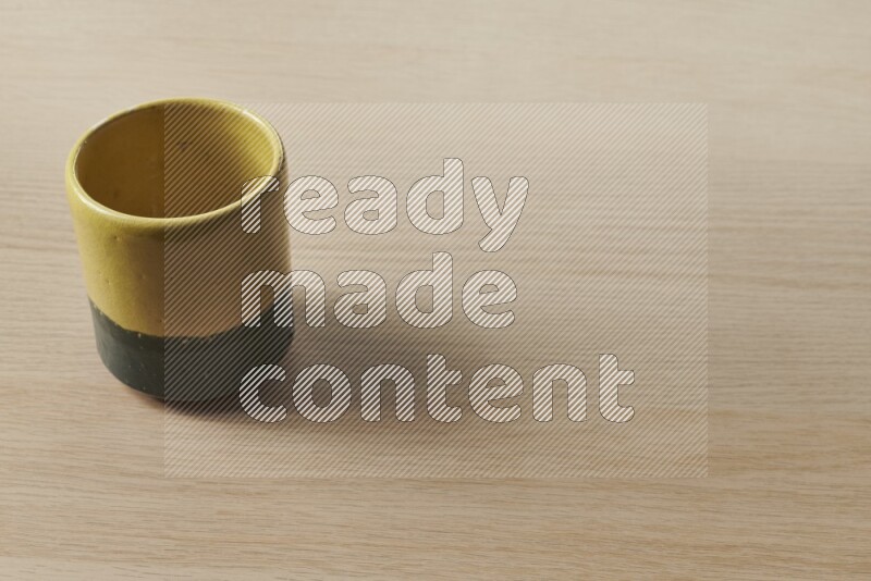 A multicolored pottery cup on light wooden background