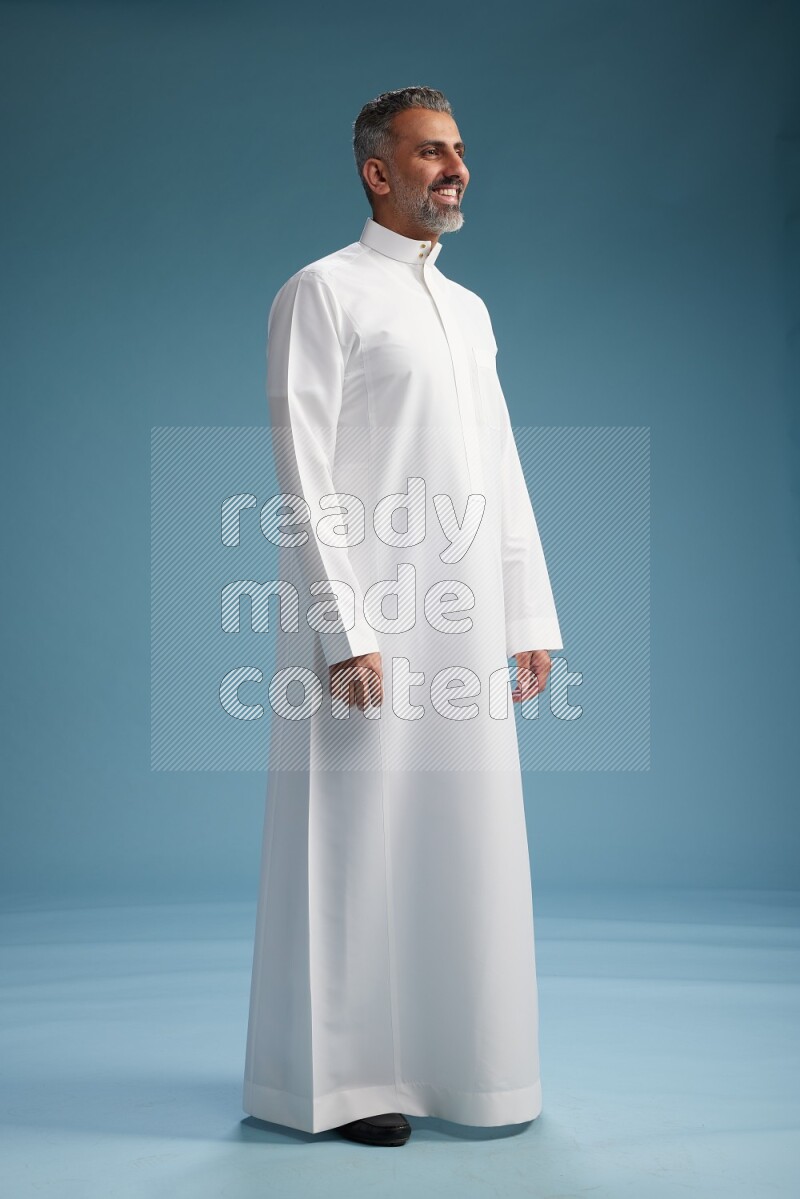 Saudi man waring thob posing to the camera on blue background