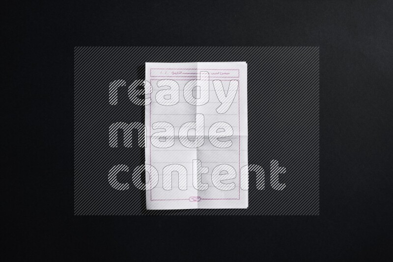 Folded notebook sheet on black background