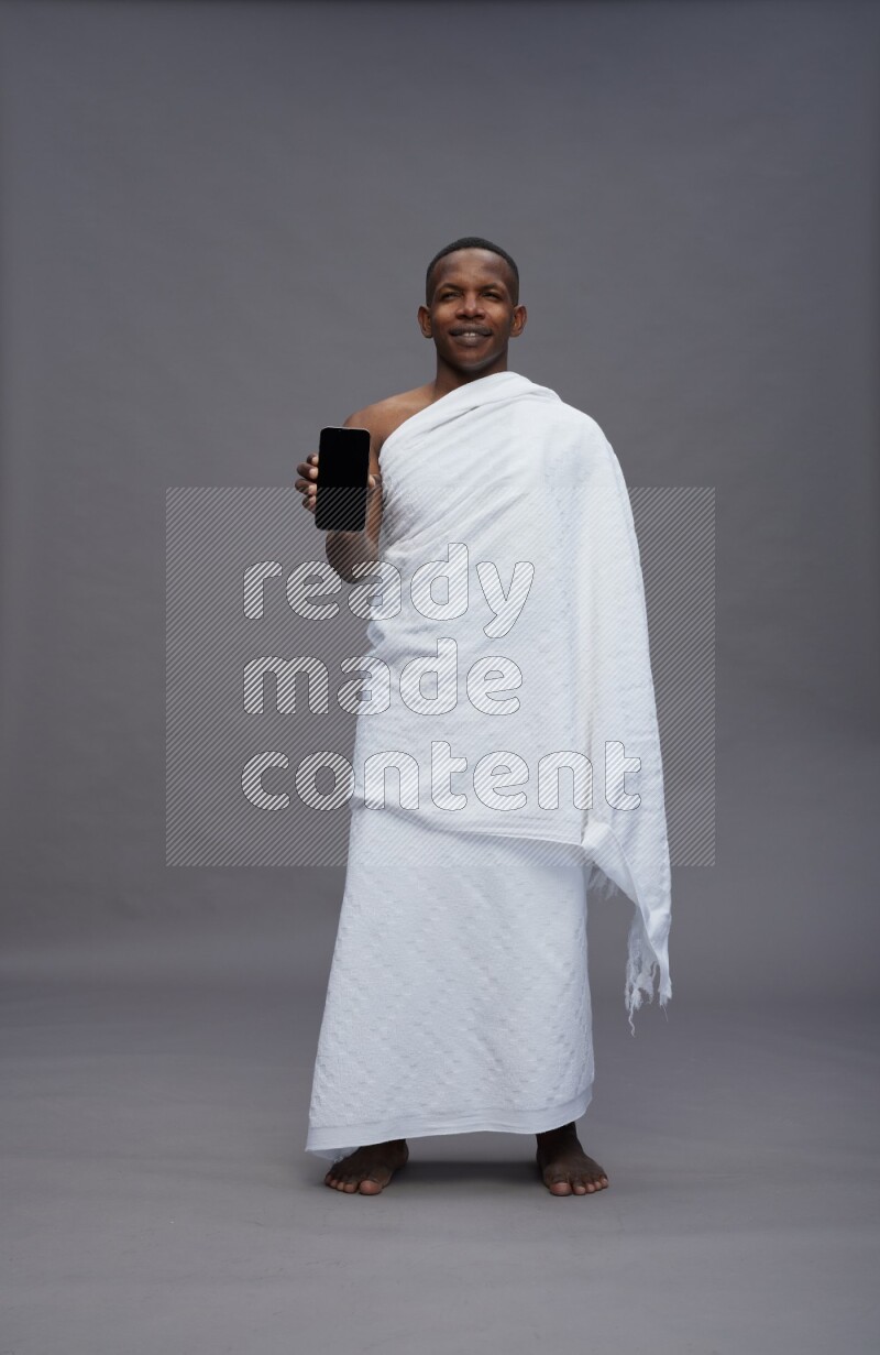 A man wearing Ehram Standing showing phone to camera on gray background