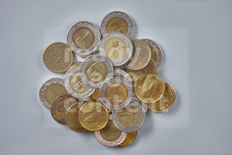 A close-up of scattered mixed Egyptian coins such as One pound, 50 and 25 piasters on grey background