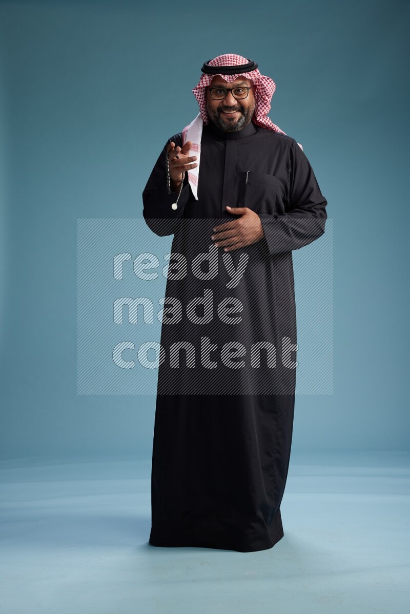 Saudi Man with shimag Standing Interacting with the camera on blue background