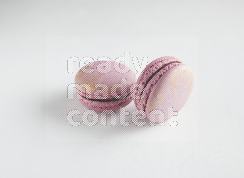 45º Shot of two Purple Strawberry macarons on white background