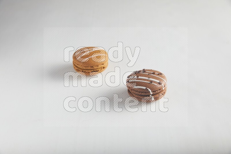45º Shot of of two assorted Brown Irish Cream, and Brown white Chocolate Caramel macarons on white background
