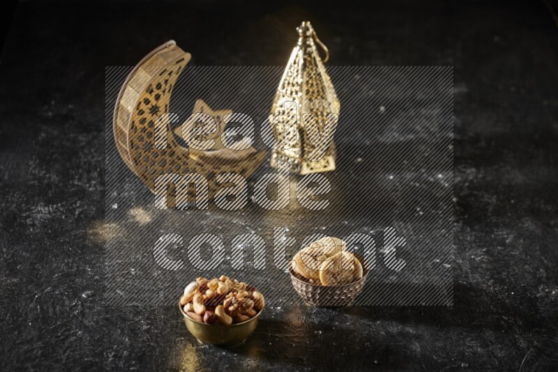 Nuts in a metal bowl with dried figs beside golden lanterns in a dark setup