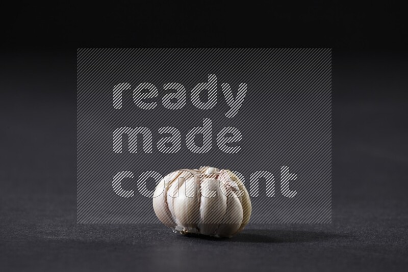 A whole garlic bulb placed on a black flooring
