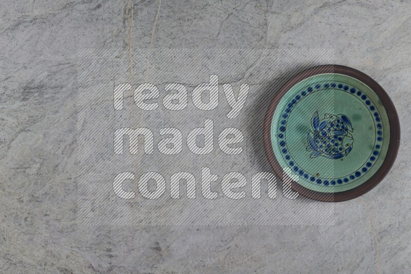 A decorative pottery plate on grey marble background
