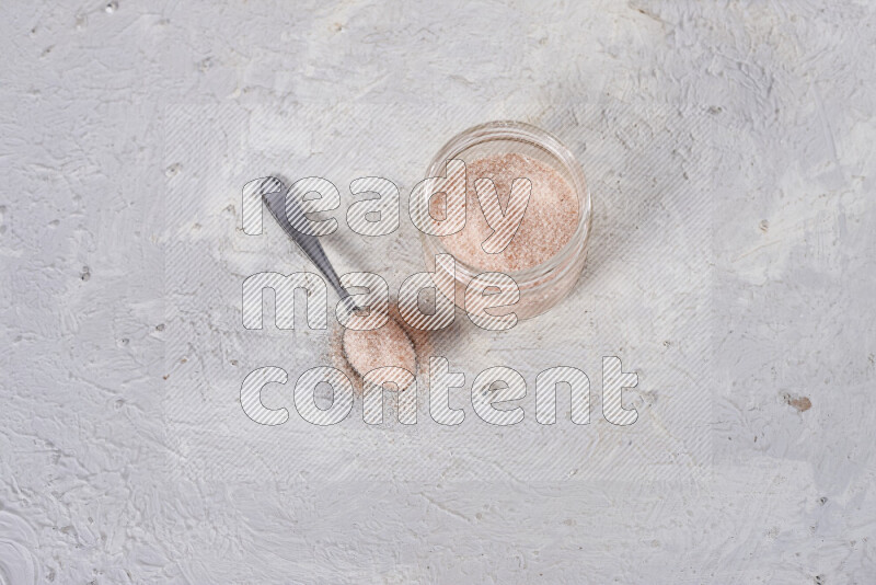 A glass jar full of fine himalayan salt on white background