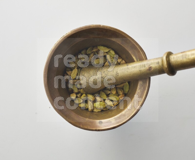 Top-view shot of Cardamon in herbs crusher on white background
