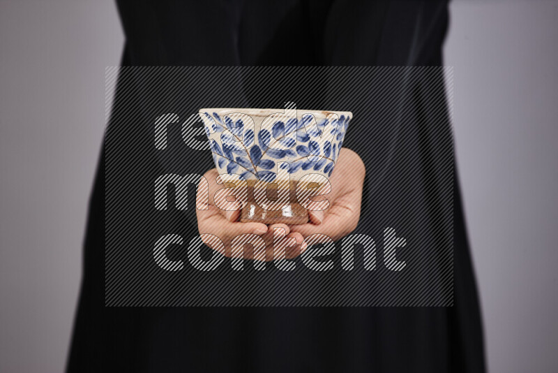 A woman in black abaya holding different pottery essentials in different positions