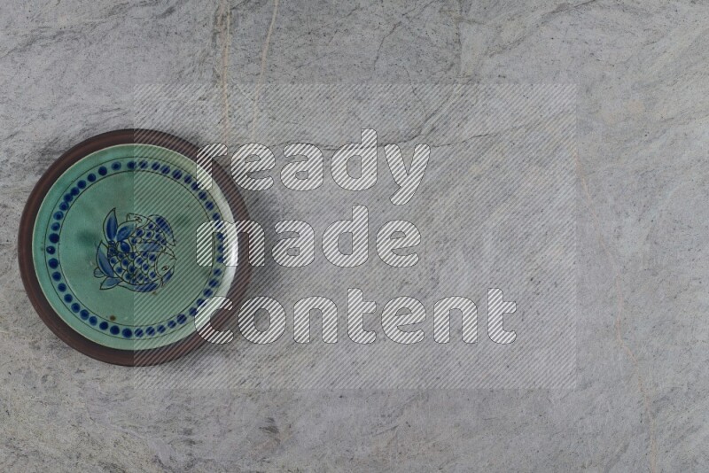 A decorative pottery plate on grey marble background