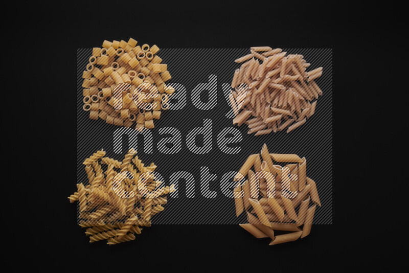 Different pasta types in bunches on black background
