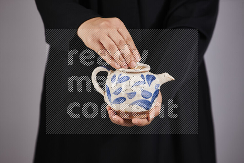 A woman in black abaya holding different pottery essentials in different positions