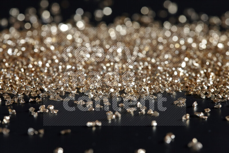 Gold shimmering fragments of glass scattered on a black background
