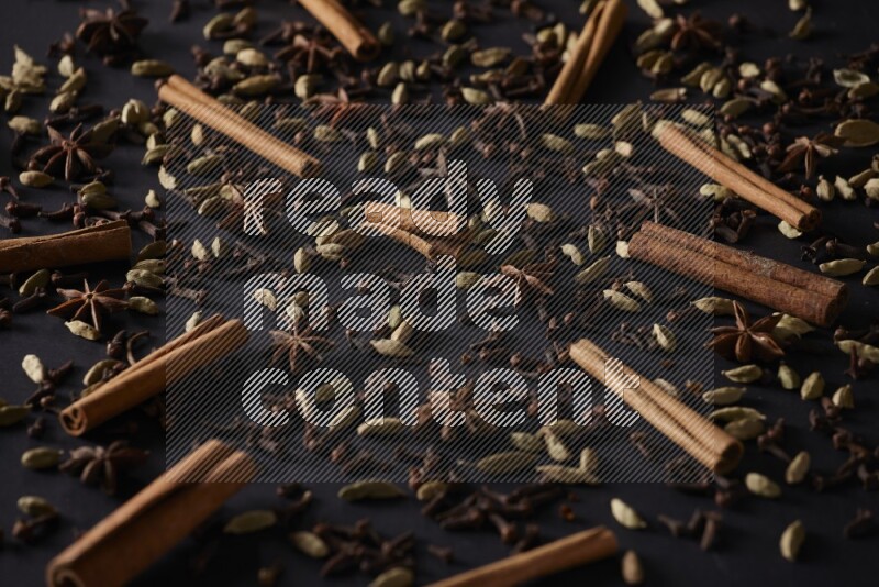 Cinnamon Sticks, Star anise, Cardamom and cloves on a black background
