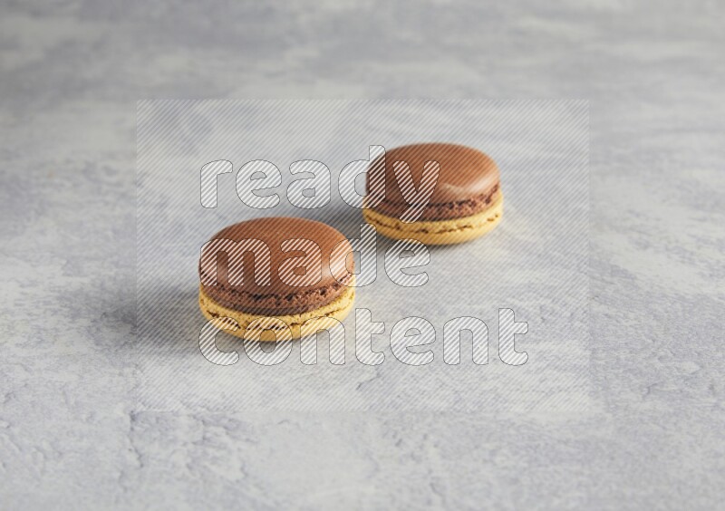 45º Shot of two Yellow and Brown Chai Latte macarons r on white  marble background
