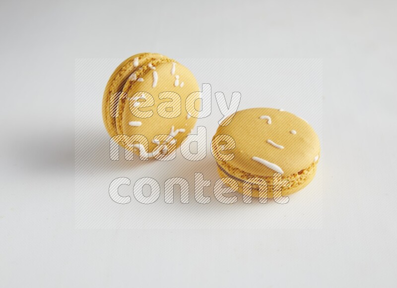 45º Shot of two Yellow Piña Colada macarons on white background