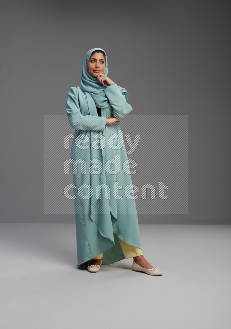 Saudi Woman wearing Abaya standing interacting with the camera on Gray background