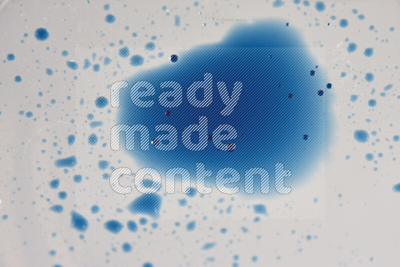Close-ups of abstract blue watercolor drops on oil Surface on white background