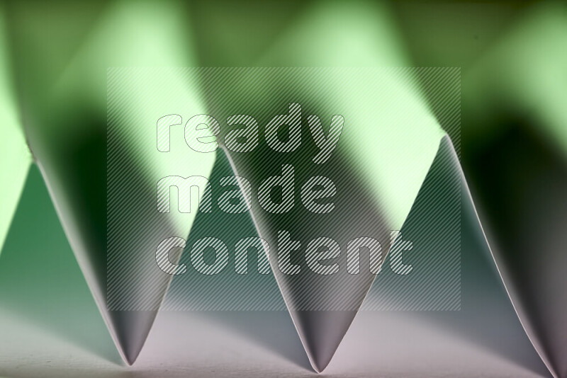 A close-up abstract image showing sharp geometric paper folds in white and green gradients