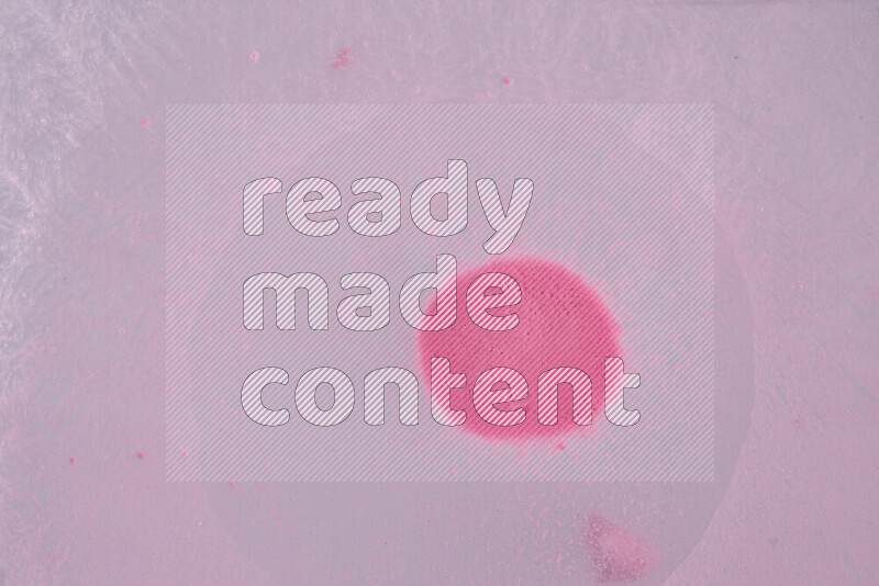 The image captures a dramatic splatter of pink paint over a white backdrop