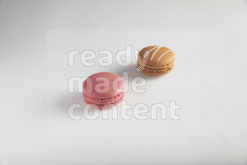 45º Shot of of two assorted Brown Irish Cream, and Pink Raspberry macarons on white background