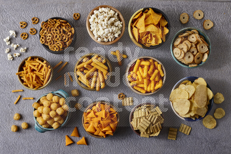 Assorted snacks in pottery bowls on grey background