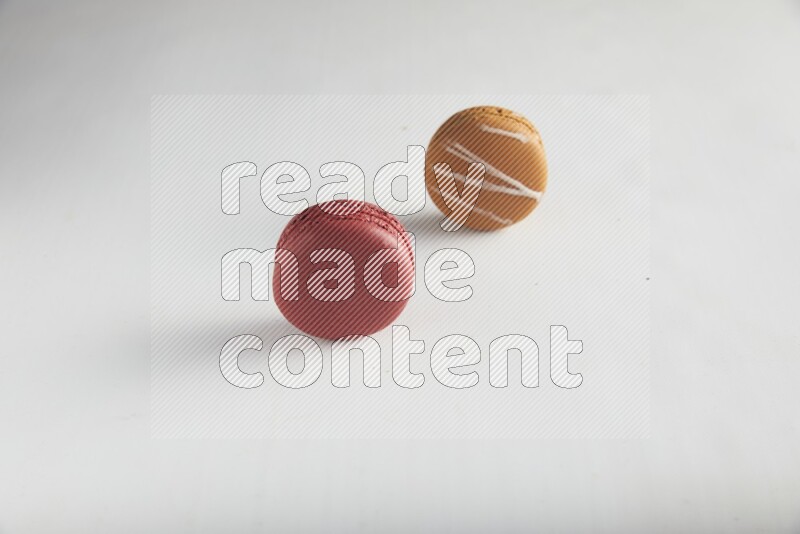 45º Shot of of two assorted Brown Irish Cream, and Red Velvet macarons on white background