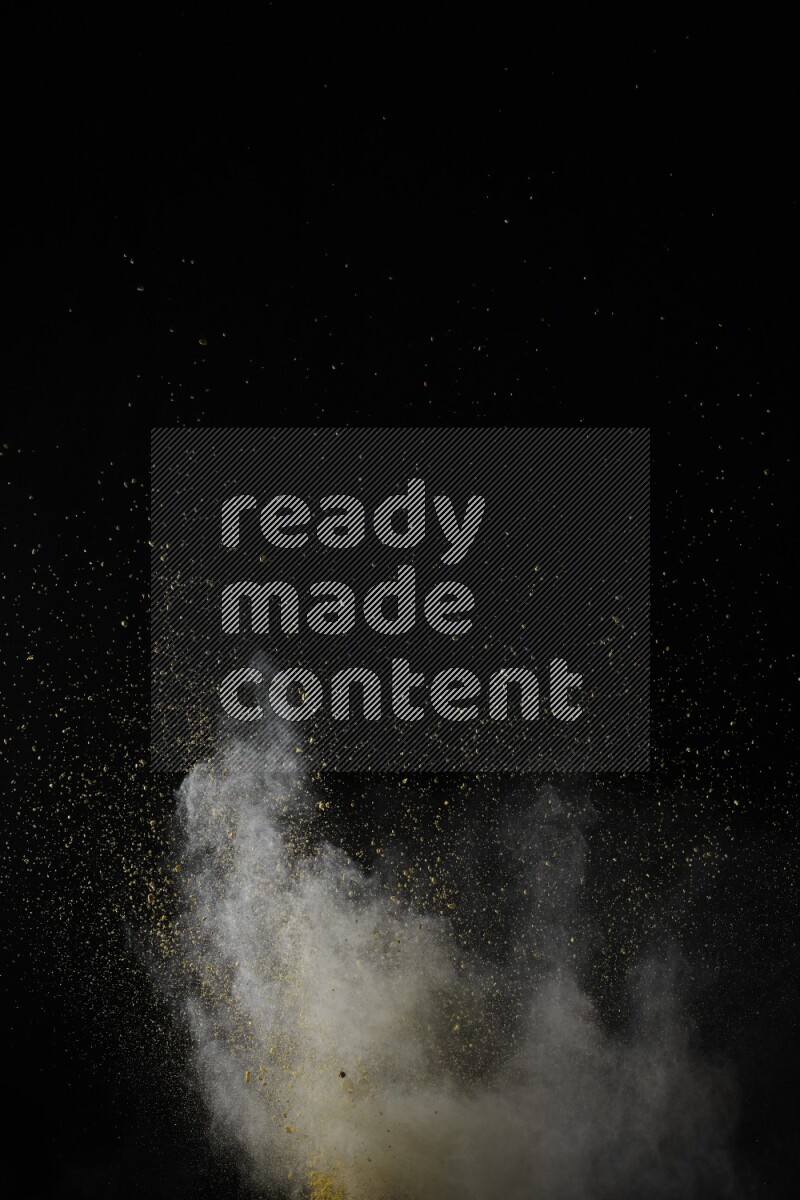 A side view of yellow powder explosion on black background