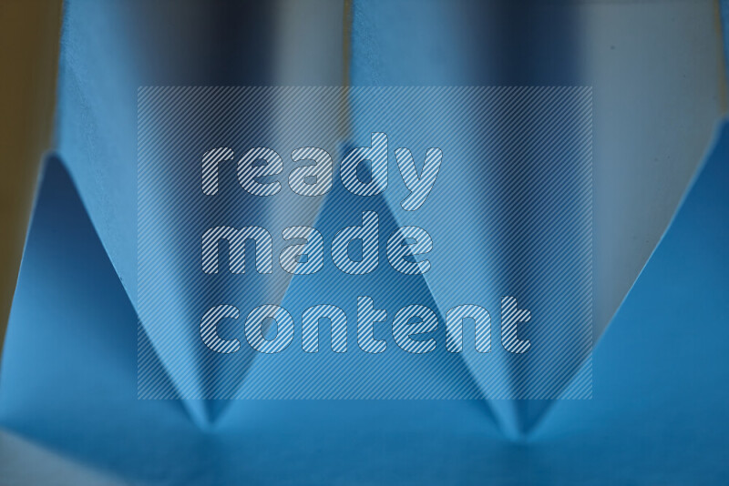 A close-up abstract image showing sharp geometric paper folds in blue gradients